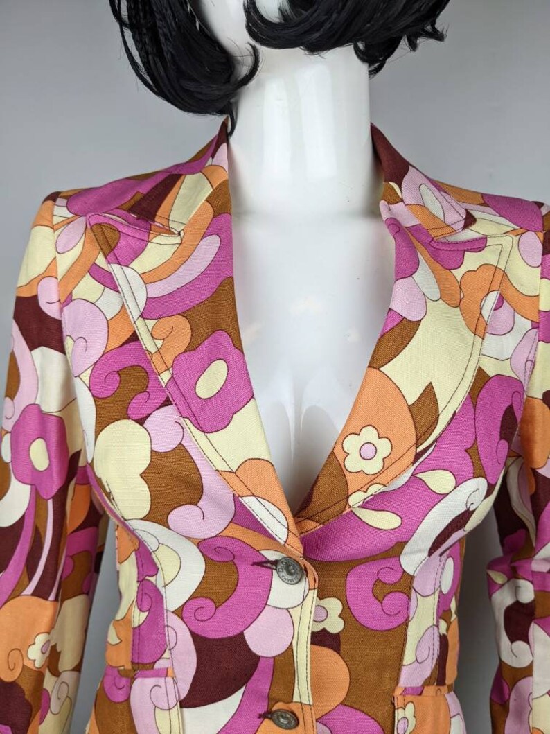 May include: A brown, pink, orange, and white patterned blazer with a single button closure. The blazer has a collar and long sleeves.