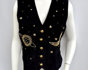 May include: Black suede vest with gold-colored star and planet embellishments. The vest has a V-neck, gold buttons, and a celestial design. The vest is sleeveless.
