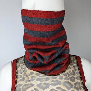 May include: A red and gray striped knit neck warmer. The neck warmer is made of a soft, comfortable material and is perfect for keeping warm in the winter.