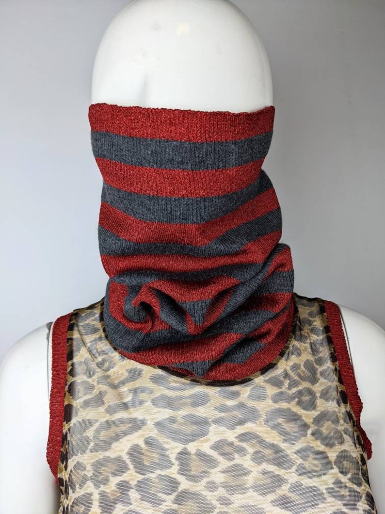 May include: A red and gray striped knit neck warmer. The neck warmer is made of a soft, comfortable material and is perfect for keeping warm in the winter.