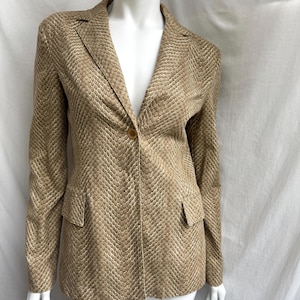 May include: A tan blazer with a snakeskin pattern. The blazer has a single-button closure, notched lapels, and two front pockets. The fabric has a subtle sheen, and the overall design is tailored and classic.