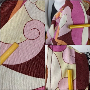 May include: Close-up of a pink, brown, orange, and white fabric with a swirling pattern. The fabric is textured and has a vintage look.