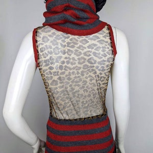 May include: A sleeveless gray and red striped sweater with a leopard print mesh panel in the back. The sweater has a high turtleneck.