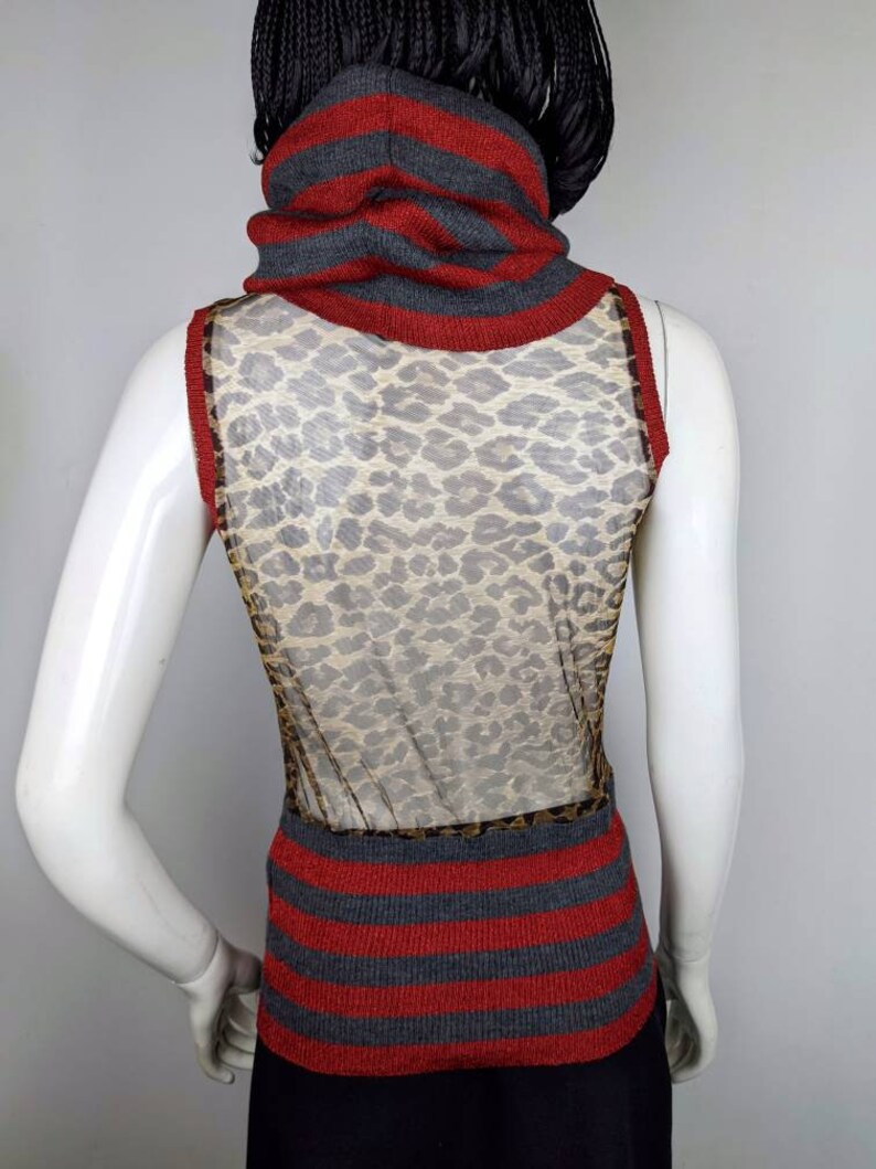 May include: A sleeveless gray and red striped sweater with a leopard print mesh panel in the back. The sweater has a high turtleneck.