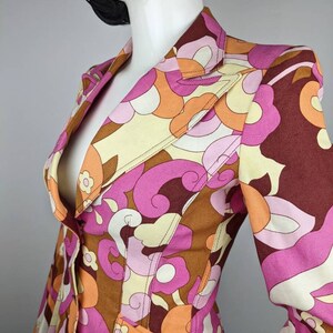 May include: A pink, brown, orange, and white patterned blazer with a single button closure.