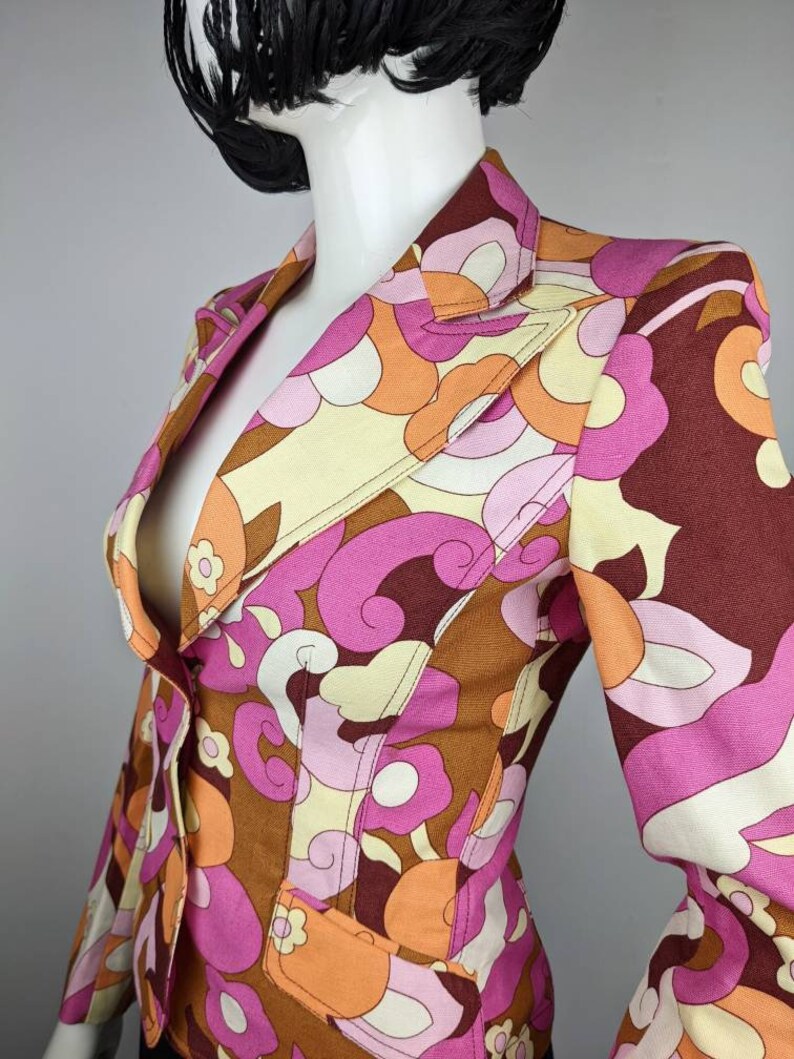 May include: A pink, brown, orange, and white patterned blazer with a single button closure.