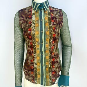 May include: A long-sleeved button-down shirt with a green mesh overlay. The shirt features a geometric pattern in shades of brown, red, and green, with gold and green embroidery and velvet accents.