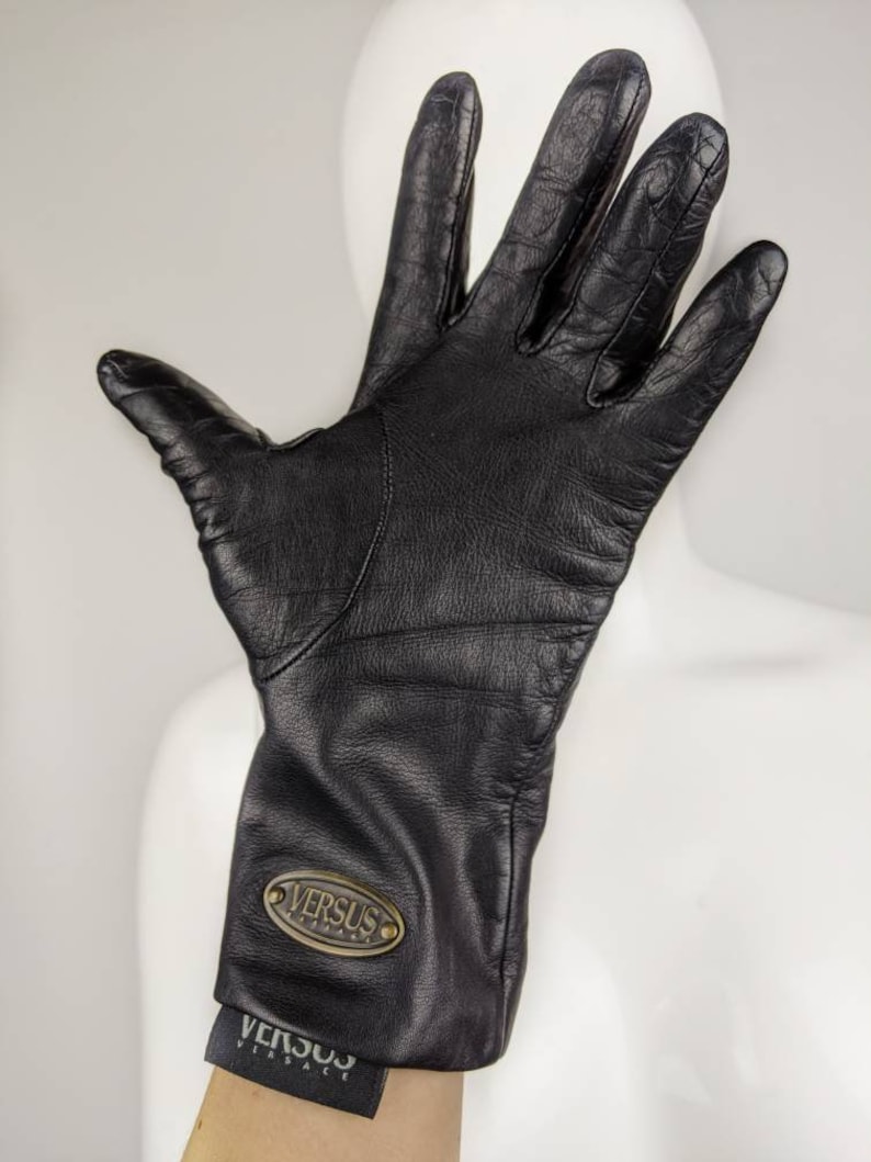 May include: Black leather gloves with a gold oval logo that says "VERSUS VERSACE".