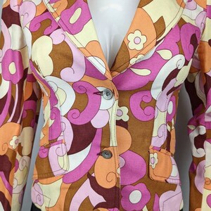 May include: A brown, pink, orange, and white patterned blazer with a button closure. The blazer has a retro 1970s style.