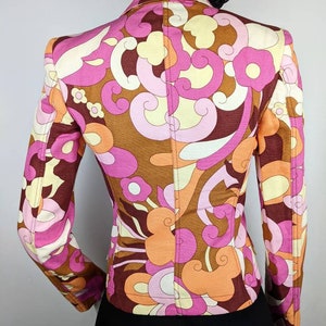 May include: A brown, pink, and orange patterned blazer with a fitted silhouette. The blazer has a long sleeve and a pointed collar.