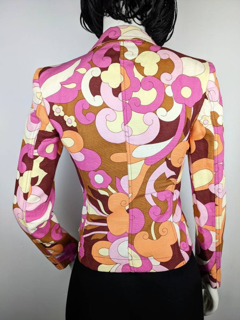 May include: A brown, pink, and orange patterned blazer with a fitted silhouette. The blazer has a long sleeve and a pointed collar.