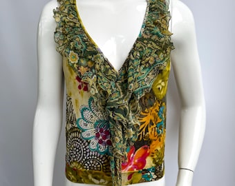 May include: A sleeveless top with a V-neck and a floral pattern in shades of green, yellow, and pink. The top features a ruffled trim around the neckline and a tie detail at the center.