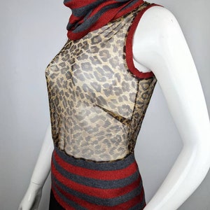 May include: A sleeveless, sheer, leopard print top with a red and gray striped turtleneck collar and hem.