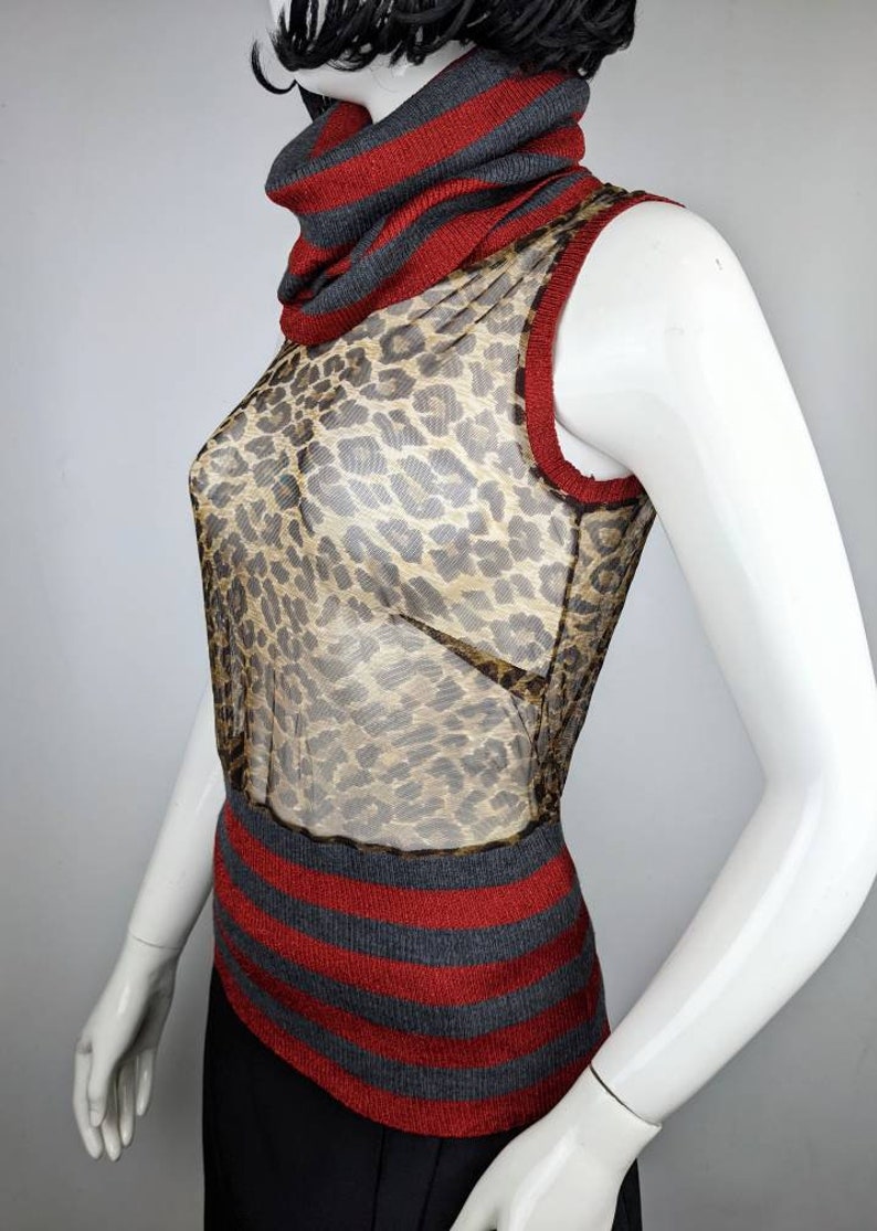 May include: A sleeveless, sheer, leopard print top with a red and gray striped turtleneck collar and hem.