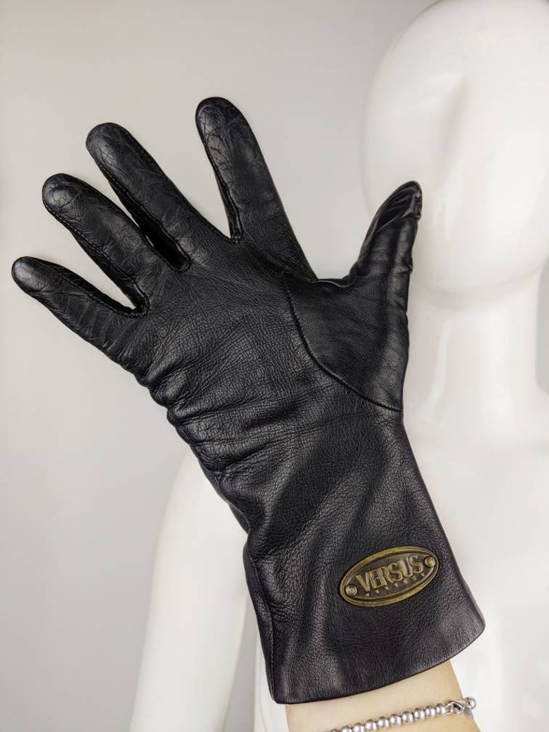 May include: Black leather gloves with a gold oval logo that says "VERSUS" on the cuff.