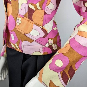 May include: A brown, pink, and cream patterned jacket with a fitted silhouette. The jacket has a button closure and long sleeves.