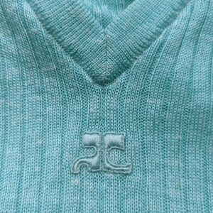 Puede incluir: Primer plano de una camisa de punto azul claro con un peque&ntilde;o logotipo bordado que dice "JC" en blanco.