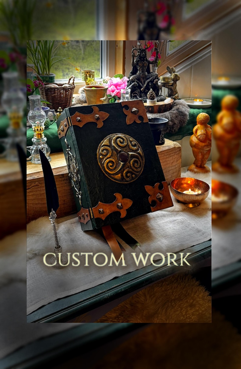 May include: A handcrafted, dark green book with ornate gold and brown accents. The cover features a central circular design and decorative corner pieces. The text "CUSTOM WORK" is displayed at the bottom of the image. A quill pen rests nearby.