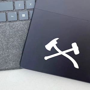 May include: A white vinyl sticker of a hammer and sickle on a black laptop.