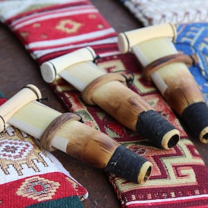 Puede incluir: Tres instrumentos tradicionales de viento de madera turcos llamados "zurna" o "ney" se muestran sobre una tela con patrones coloridos. Los instrumentos están hechos de madera y tienen una cubierta de cuero negro en la parte inferior.
