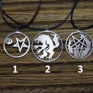 Op de afbeelding: Drie zilveren kettingen met verschillende hangers. De eerste hanger heeft een pentagram met een cirkel in het midden. De tweede hanger heeft een wolf- of hondenachtig wezen. De derde hanger heeft een pentagram met een wolf- of hondenachtig wezen aan elke kant.