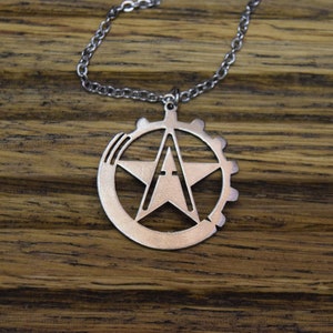 May include: A silver necklace with a pendant featuring a five-pointed star with a letter 'A' inside, surrounded by a gear-like circle.