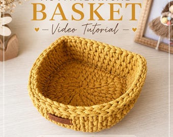 May include: Mustard yellow asymmetrical crochet basket. The basket has a square shape with rounded corners and a textured surface. The text "ASYMMETRICAL BASKET - Video Tutorial" is at the top. The bottom of the image has the text "VIDEO TUTORIAL | PDF INSTRUCTIONS".