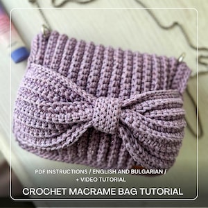 Op de afbeelding: Een lavendelkleurige macramé tas gehaakt met een strikdetail. De tas heeft een kettingriem en is gemaakt van getextureerd garen. De tekst op de afbeelding luidt "CROCHET MACRAME BAG TUTORIAL".
