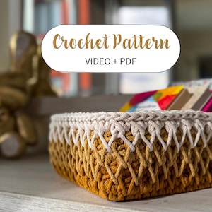 May include: A handcrafted crochet basket with a gradient of yellow and beige yarn. The basket features a textured, woven design and a thick, braided rim. The text "Crochet Pattern VIDEO + PDF" is displayed on a white oval.