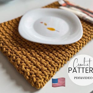 Puede incluir: Un salvamanteles de ganchillo amarillo mostaza con un plato blanco encima. El plato tiene un diseño de hoja simple. Se ven un tenedor y un cuchillo. La imagen incluye el texto "Crochet Pattern PDF & Video" y una bandera estadounidense.