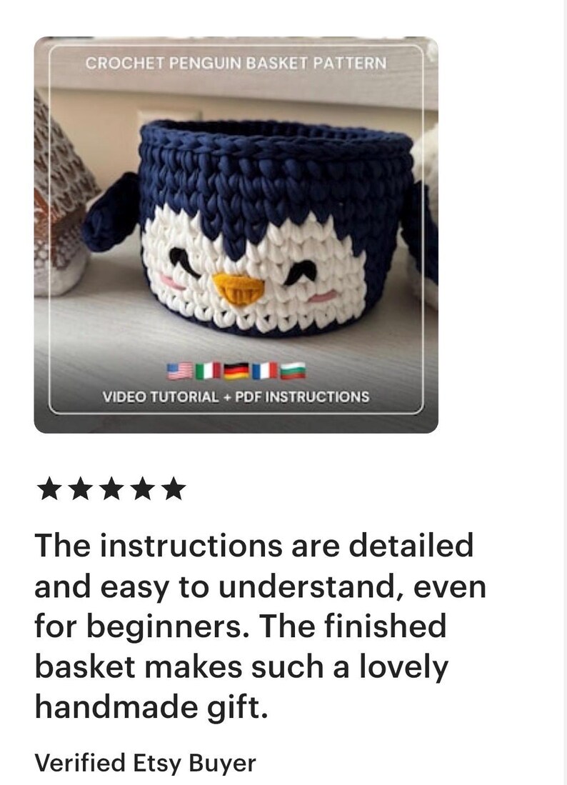 May include: A handmade crochet penguin basket in navy blue and white. The basket has a penguin face design with black eyes, a yellow beak, and pink cheeks. The text "CROCHET PENGUIN BASKET PATTERN" is at the top.