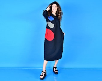 May include: A black long-sleeved dress with a cowl neck and colorful abstract design. The dress has a loose fit and falls to the knees.