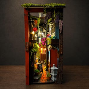 Pode incluir: Um diorama em miniatura de um beco estreito com pilares vermelhos, lanternas suspensas e arranjos florais vibrantes. A cena inclui uma lanterna de pedra, uma pequena lousa e texto em japonês em painéis de madeira verticais.