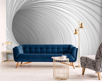 May include: A modern living room featuring a blue velvet sofa with wooden legs, a patterned armchair, and a gold side table. The wall is decorated with a white and gray abstract design, and a gold floor lamp provides additional lighting.