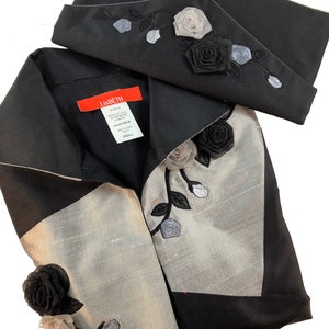May include: A black and silver silk blouse with a black collar and a decorative rose design. The blouse has a label that reads "Lisbeth" and "100% Silk".