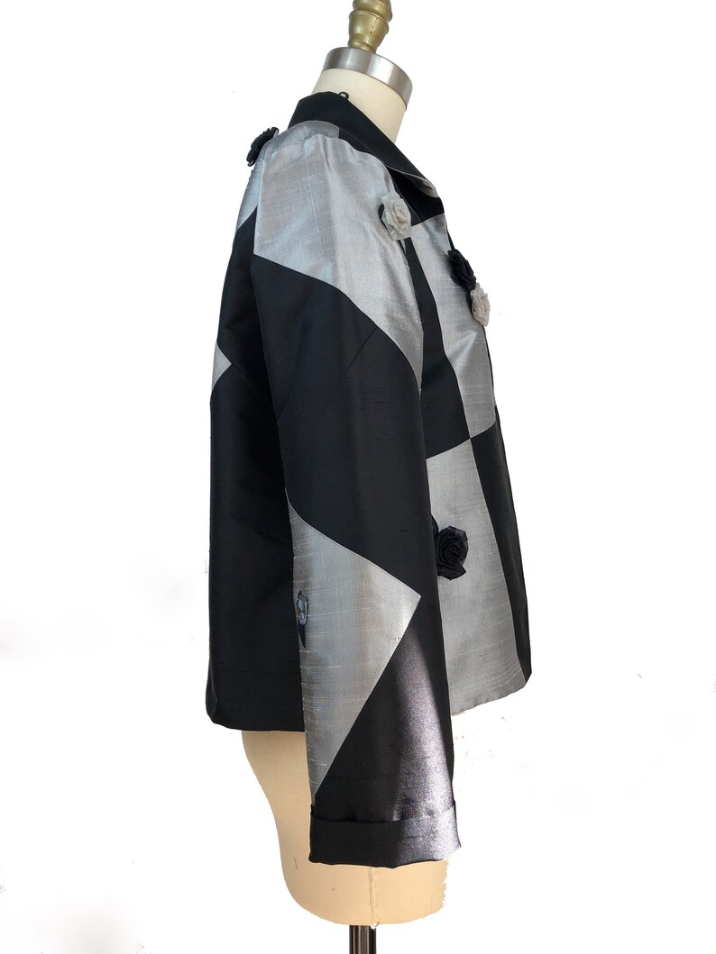 May include: A black and silver jacket with a geometric pattern and floral embellishments.