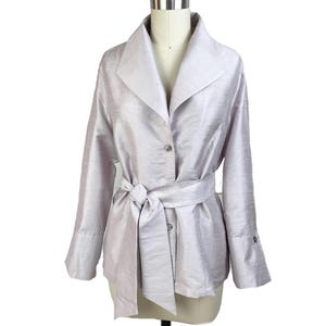 Puede incluir: Chaqueta lavanda clara con cinturón anudado a juego. La chaqueta tiene cuello con solapas, mangas largas y dos botones. La chaqueta se exhibe en un maniquí.