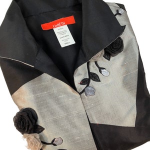 May include: A black and silver silk blouse with a black rose and leaf embroidery. The blouse has a collar and a button closure. The label reads "Lisbeth 100% Silk Dry Clean Only Small".
