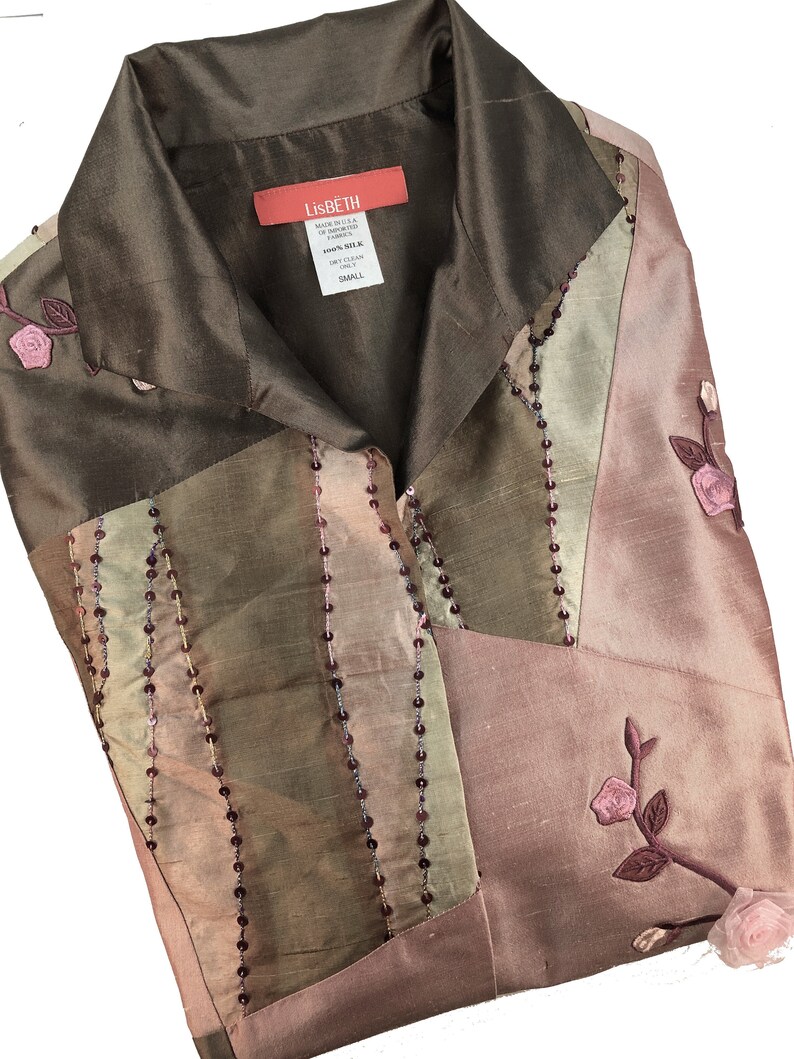 K&ouml;nnte beinhalten: Eine braune, gr&uuml;ne und rosafarbene Seidenbluse mit Perlenbesatz und Blumenstickerei. Die Bluse hat einen Kragen und einen Knopfleisten vorne. Das Etikett lautet "LisBeth" und "Small".