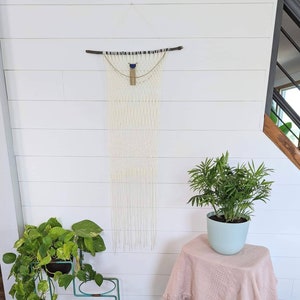 Macrame hanging w/ vintage gold and blue chain necklace on dark natural wood stick