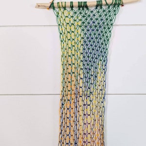 Rainbow string macrame wall hanging on natural wood stick