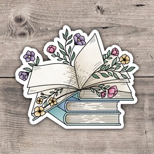 May include: A sticker featuring an open book with a stack of books underneath. The book is surrounded by a floral arrangement with pink, purple, and yellow flowers.