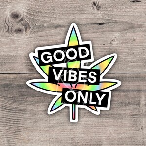 May include: A sticker with a rainbow-colored marijuana leaf and the text "GOOD VIBES ONLY" in black.