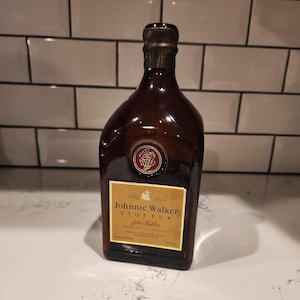 Pode incluir: Uma garrafa de vidro castanho de licor Johnnie Walker, com um r&oacute;tulo dourado e uma tampa castanha escura. O r&oacute;tulo diz "Johnnie Walker Liqueur" e "Produto da Esc&oacute;cia". A garrafa cont&eacute;m 750 ml de &aacute;lcool a 40%.