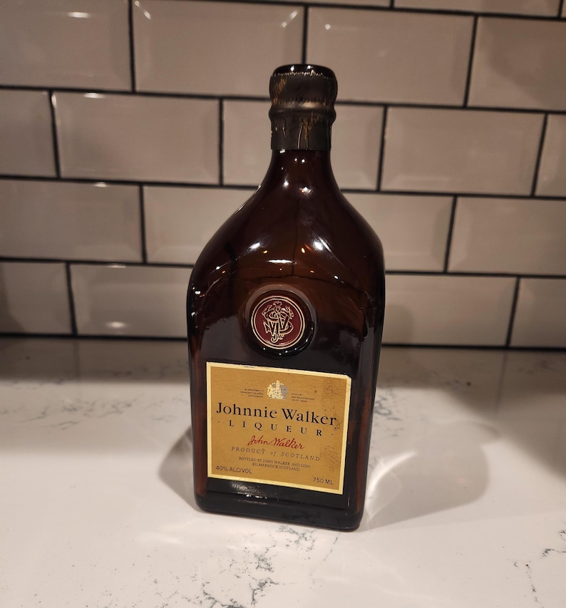 Pode incluir: Uma garrafa de vidro castanho de licor Johnnie Walker, com um r&oacute;tulo dourado e uma tampa castanha escura. O r&oacute;tulo diz "Johnnie Walker Liqueur" e "Produto da Esc&oacute;cia". A garrafa cont&eacute;m 750 ml de &aacute;lcool a 40%.