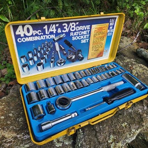 May include: Open yellow toolbox with a blue interior, containing a 40-piece combination ratchet socket set. The set includes various sockets, ratchets, and extensions. The toolbox is open, revealing the tools neatly arranged inside.