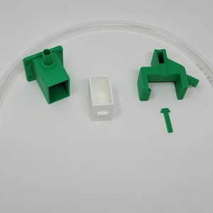 May include: A set of green 3D printed parts for a DIY project. The set includes a connector with a hose barb, a clamp, a small box, and a screw. A clear plastic tube is also included.