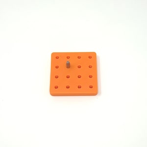 May include: An orange plastic pegboard with a single metal peg inserted in the center.