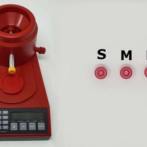 May include: Red reloading scale with a digital display and a red hopper. The scale has a black keypad with numbers and functions. The scale is labeled "Hornady" and "Automatic Powder Dispenser". There are three red targets labeled "S", "M", and "L".
