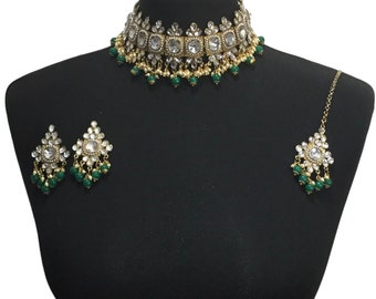 May include: A gold choker necklace with white stones and green beads. Matching earrings and a maang tikka are also included.